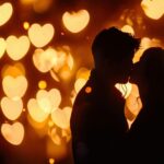 Ein Paar in inniger Umarmung, das sich leidenschaftlich küsst, vor einem Hintergrund aus warmen, leuchtenden Herzen. Die Silhouette des Paares wird von den romantischen Lichtpunkten betont, die eine stimmungsvolle und emotionale Atmosphäre schaffen.